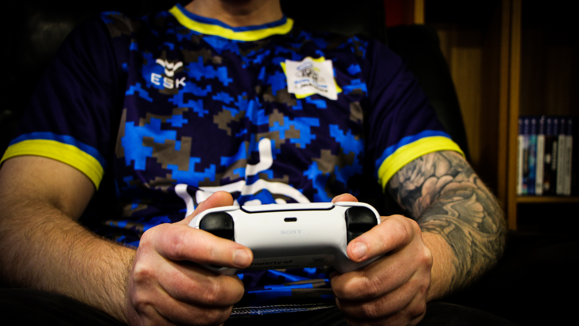 young man holding console controller wearing game on t-shirt