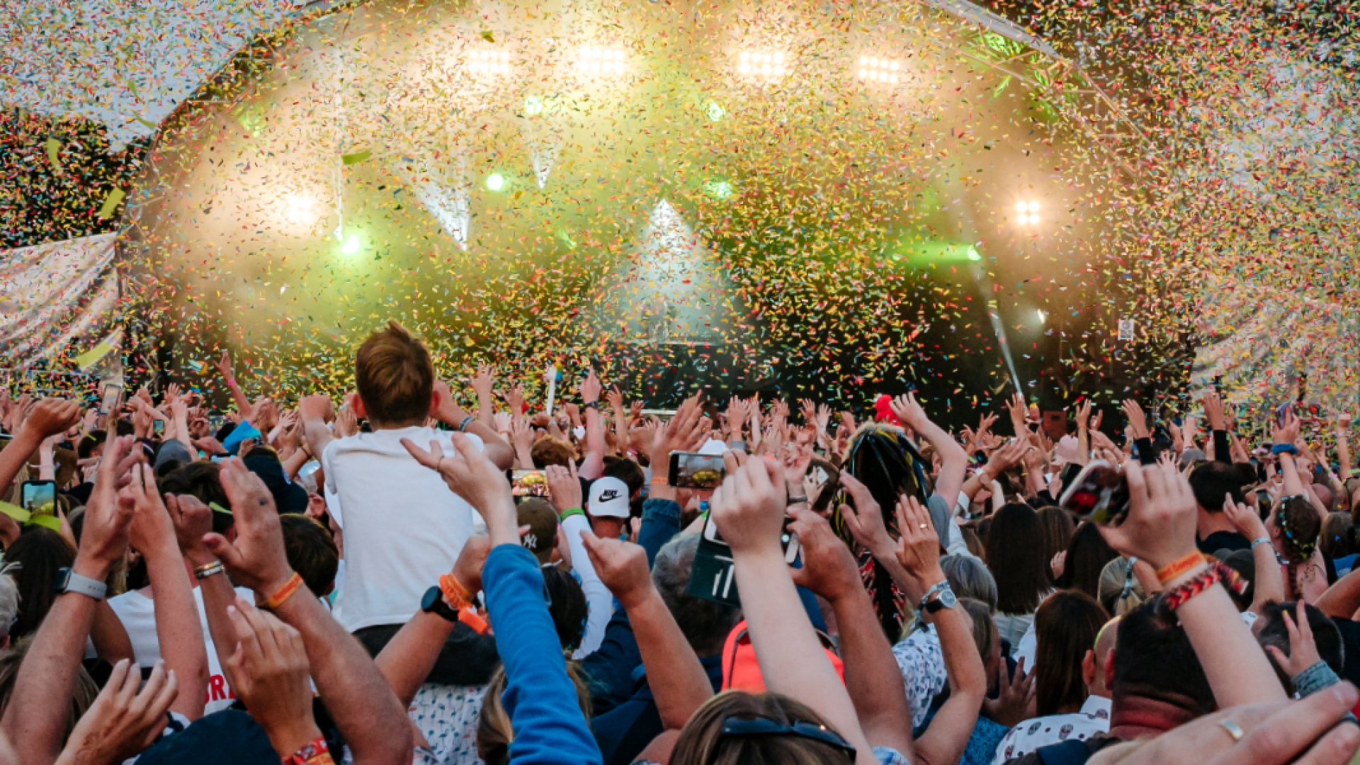 Crowd hands in front of stage at CarFest with lots of confetti falling