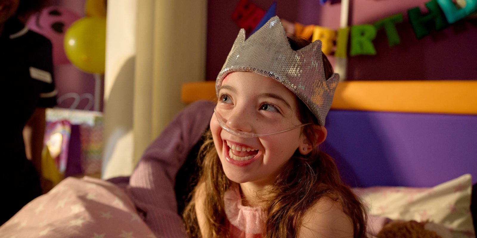 Little girl in a hospice smiling with a party hat on